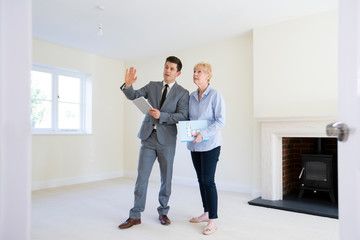 Realtor With Digital Tablet Showing Senior Woman Looking To Downsize Around Retirement Home