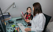 © David Pereiras - Woman teleworking with daughter showing her a drawing. Selective focus on girl in background