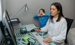 © David Pereiras - Woman telecommuting making a video conference with her daughter grimacing behind. Selective focus on woman in foreground