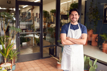 Wall Mural - Portrait Of Smiling Male Owner Of Florists Standing In Doorway Surrounded By Plants