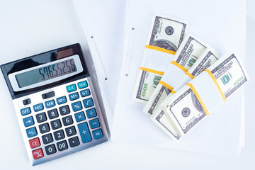 Wall Mural - Included calculator next to the money. Calculator next to packs of dollars. Calculation of expenses using a calculator. Preparation of income statement. Concept - calculation of return on investment