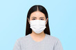 © Atstock Productions - Asian woman wearing medical face mask isolated on light blue background