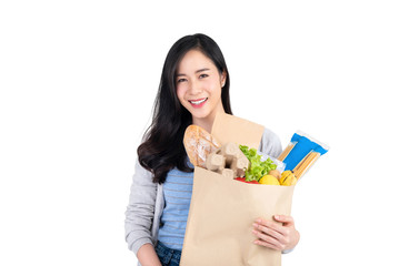 Beautiful smiling Asian woman holding paper shopping bag full of food and groceries isolated on white background