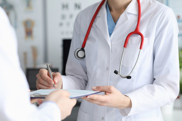 Female doctor signs patient card with diagnosis. Help qualified doctors. Admission department equipped with everything necessary for diagnosis and treatment patients. Drug withdrawal acute conditions