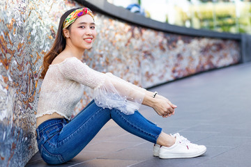 Portrait of smiling beautiful sexy slim Asian woman sitting on the floor