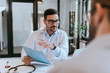 © bnenin - Doctor holding a file and talking with a patient, portrait.
