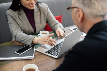 Wall Mural - cropped view of smiling businesswoman using laptop and talking with businessman during business meeting