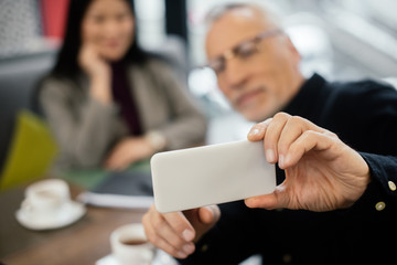 Wall Mural - selective focus of businessman taking selfie with businesswoman in cafe