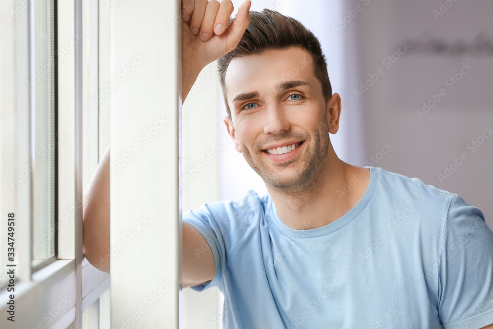 Handsome young man with healthy teeth at home