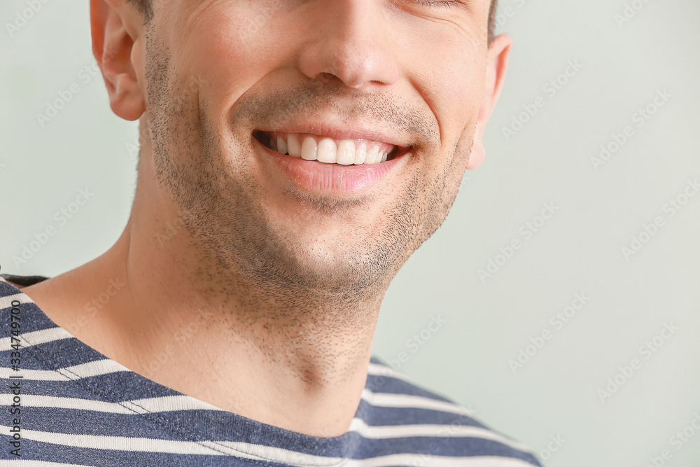Handsome young man with healthy teeth on white background, closeup