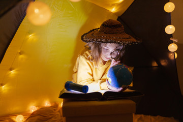 Wall Mural - young girl student learning and homeschooling in a home made tent with glowing light balls.