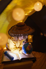 Wall Mural - young girl student learning and homeschooling in a home made tent with glowing light balls.