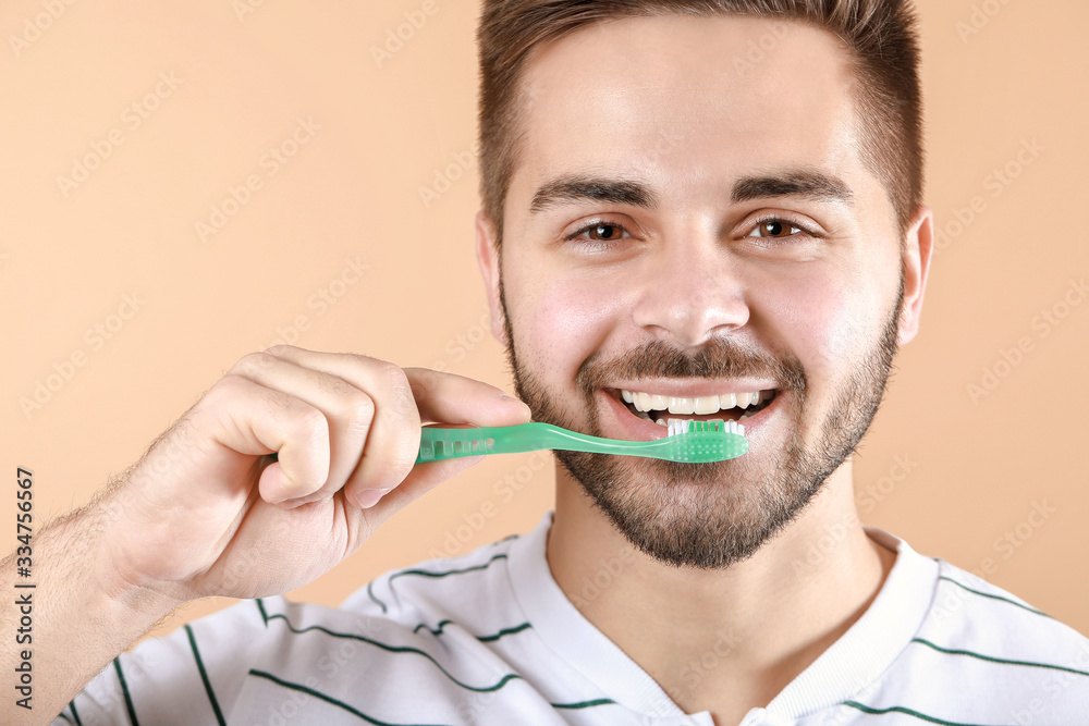 Happy smiling young man with tooth brush on color background