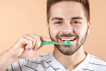 Wall Mural - Happy smiling young man with tooth brush on color background