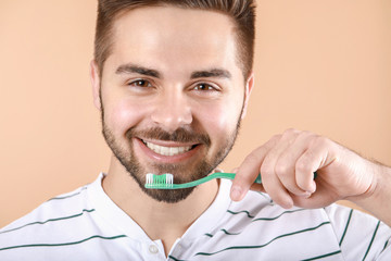 Wall Mural - Happy smiling young man with tooth brush on color background