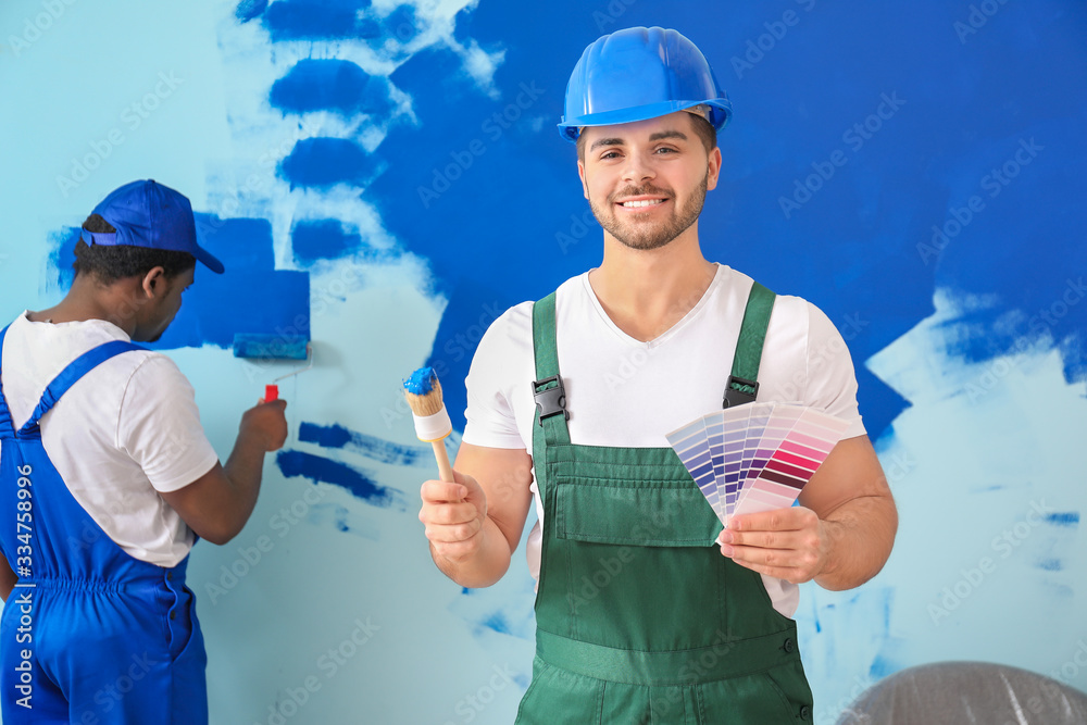 Male painters doing repair in room