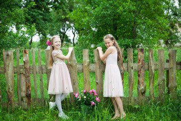 Wall Mural - Beautiful little girls with metal bucket with peonies