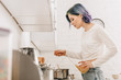 © LIGHTFIELD STUDIOS - Selective focus of girl with colorful hair putting pasta in pan near kitchen stove