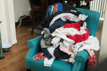 Pile of laundry of clothes on colorful chair in home