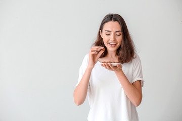 Sticker - Beautiful young woman eating tasty chocolate candies on white background