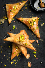 Arabe Phyllo Sweets. Feta Cheese Phyllo Triangles Pies With Honey And Pistachios, Selective Focus. Cooking Sweets Turkish, Or Arabic Traditional Ramadan Pastry Dessert On A Dark Background. Top View.