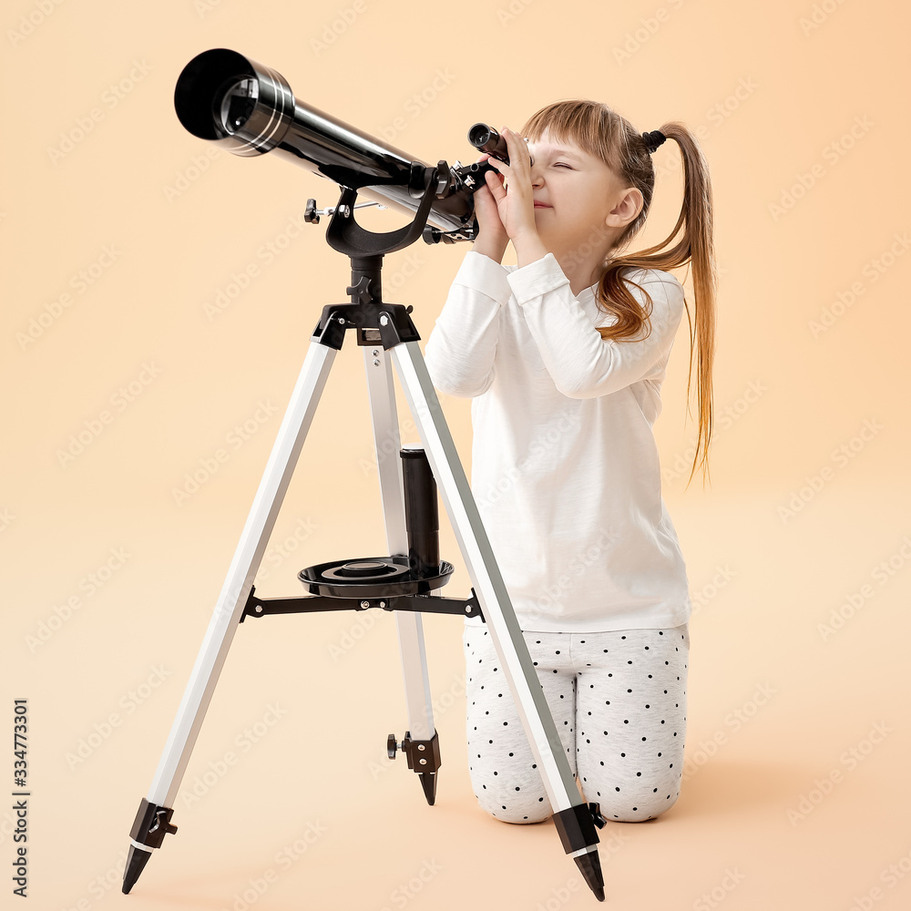Cute little girl with telescope on color background