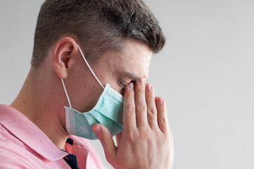 Portrait of ill dark hair european man in surgery face mask in pink polo having headache on white background