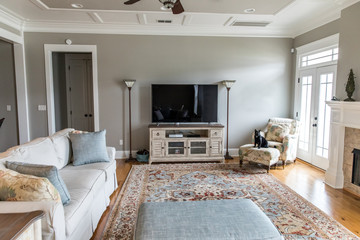 a bright and airy neutral beige living room den in a new construction house with a television and lots of natural light and furniture
