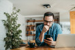 © bnenin - Portrait of a puzzled man looking at smart phone, sitting at table at home.