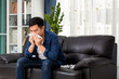 © tong2530 - healthcare concept, allergy and people concept - sick asian man blowing his runny nose in paper tissue sit on the sofa at home.