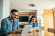 © bnenin - Portrait of a handsome smiling man using laptop, woman in the background reading letter.