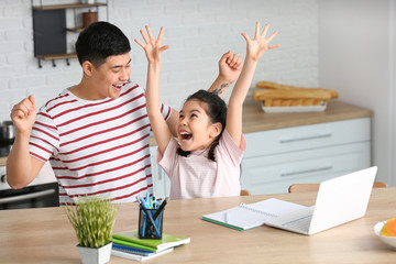 Wall Mural - Father helping his little daughter to do lessons at home