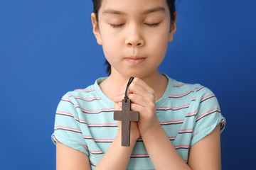 Canvas Print - Cute little Asian girl praying on color background