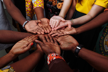 Hands of happy group of multinational African, latin american and european people which stay together in circle