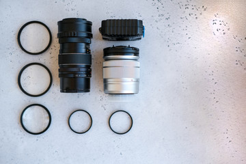 Two lenses and filters to them, adapter rings and a box with flash drives on grey backgrond. Flat lay composition with equipment for photographer