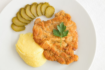 Wall Mural - wiener schnitzel decorated with parsley garnished with potato and pickled cucumber