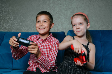 Boy and girl playing video games. Brother and sister compete with joysticks in their hands. Children have fun.