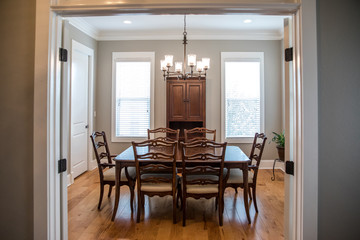 formal dining room with a set of wood table and chairs and a chandelier with windows and natural lig