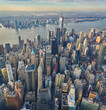 Vertical aerial panorama of downtown manhattan financial business district with high density modern skyscraper office towers and the Hudson river seen at golden hour