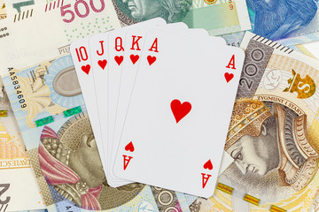 Royal straight flush in hearts, playing cards on Polish currency zloty background