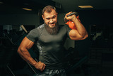 Bodybuilder doing exercises with dumbbells in a dark gym