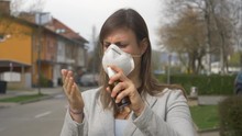 SLOW MOTION, CLOSE UP, PORTRAIT: Scared Young Woman Wearing A Protective Face Mask Sprays Sanitizer All Over Herself. Paranoid Businesswoman Covers Herself In Hand Disinfectant Before Going To Work.
