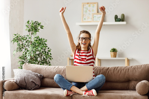 Cuadros en Lienzo Glad woman celebrating good news while working on laptop at home.