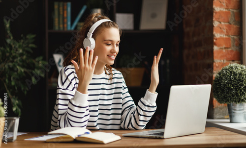 Cuadros en Lienzo Excited woman in headphones having conversation on video chat while using laptop at home