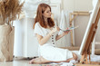 © Mira - portrait of a beautiful young red-haired girl with a palette of colors and a brush in her hands painting a picture