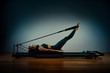 © Georgii - Young girl doing pilates exercises with a reformer bed. Beautiful slim fitness trainer on reformer gray background, low key, art light. Fitness concept