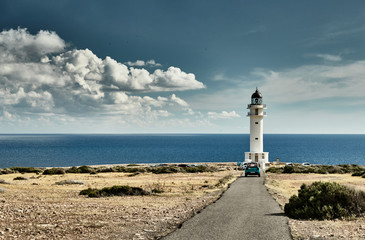 Lighthouse on the Formentera island, Spain, the blue sky with white clouds, without people, car is on a path to lighthouse