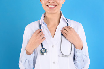 Canvas Print - Young doctor with stethoscope on blue background, closeup