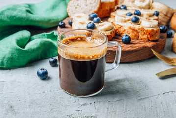 Wall Mural - Buckwheat healthy bread with peanut butter, banana and blueberry on wooden board over concrete background. Selective focus. Summer breakfast.