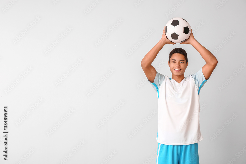 Young African-American football player on light background